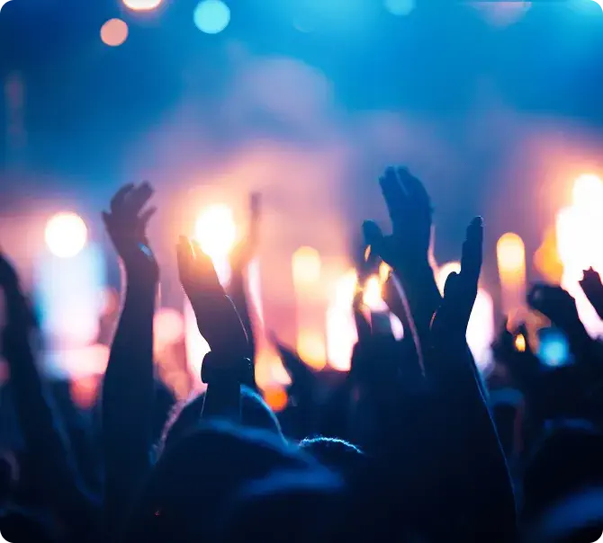 Foule enthousiaste, mains levées, lumières bleues et oranges illuminant l'ambiance festive.